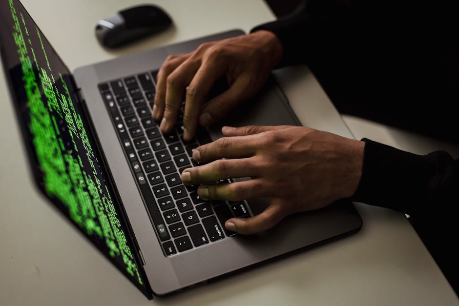 Person in a dim room using a laptop showing suspicious hacking activity