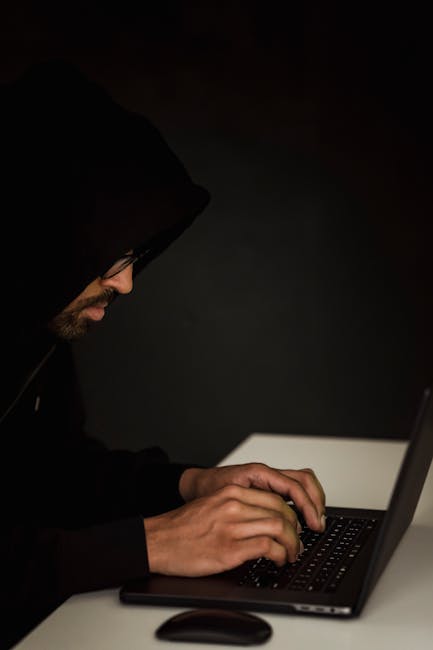 Person typing code on a laptop in a dark room, symbolizing active WordPress attacks